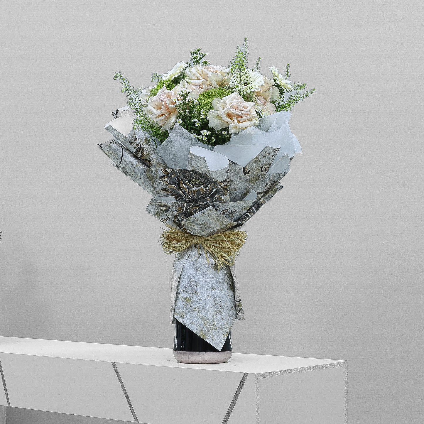Pale pink rose bouquet with white fillers and greenery, wrapped in vintage floral paper and raffia ribbon – nostalgic floral arrangement